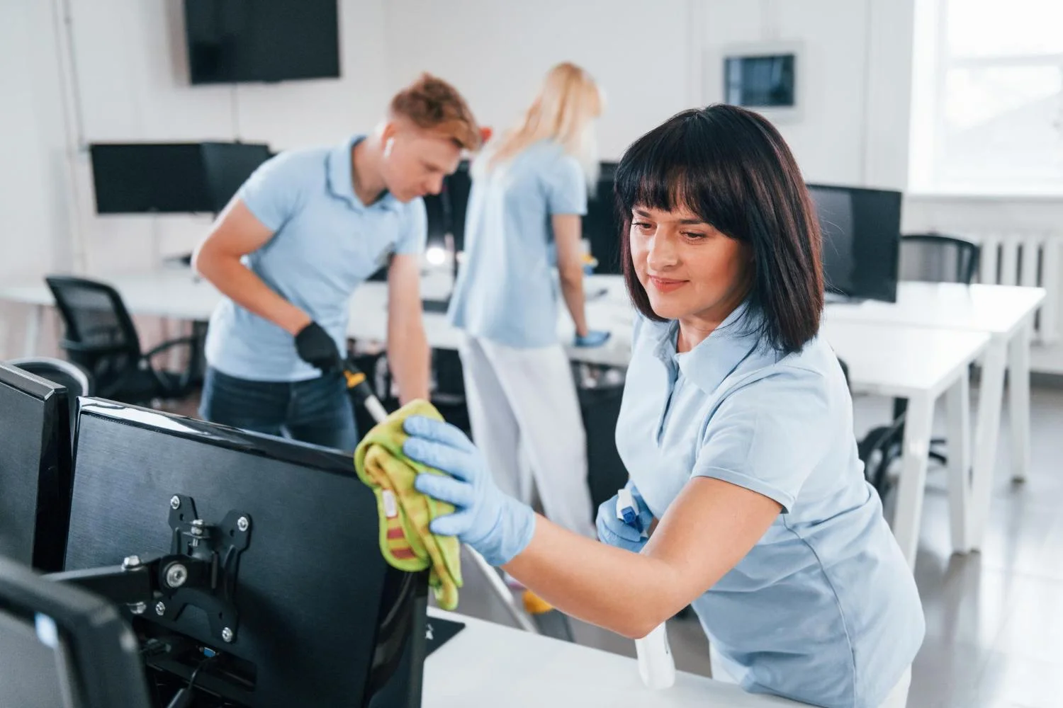 Reinigungsteam reinigt Bildschirme und Arbeitsplätze in einem Büro